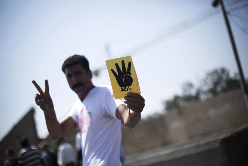 Seorang pengunjuk rasa memegang kartu kuning empat jari dengan tulisan Rabaa saat aksi unjuk rasa di dekat masjid Al-Nour di Kairo, Jumat (23/8).   