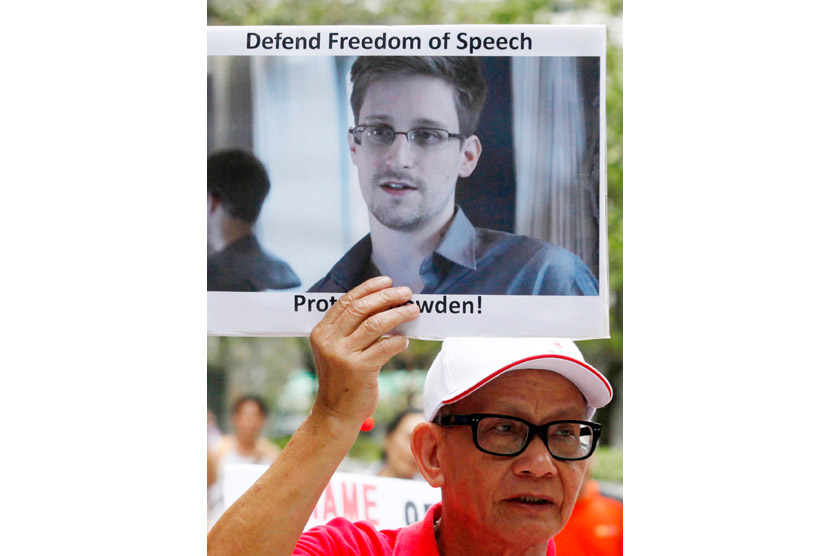  Seorang pengunjuk rasa memegang poster foto Edward Snowden, mantan karyawan CIA yang membocorkan informasi rahasia tentang program pengintaian AS, di luar gedung Konsulat Jenderal AS di Hong Kong, Kamis (13/6).    (AP/Kin Cheung)