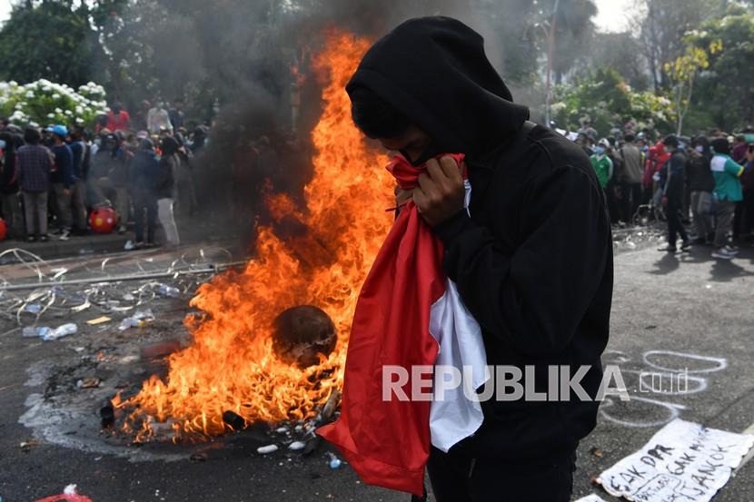 Seorang pengunjuk rasa mencium bendera merah putih saat unjuk rasa menolak Undang-undang Cipta Kerja di depan Gedung Negara Grahadi, Surabaya, Jawa Timur, Kamis (8/10/2020). Aksi yang dikuti ribuan orang dari berbagai elemen mahasiswa dan buruh tersebut berakhir ricuh dan mengakibatkan sejumlah fasilitas umum rusak.
