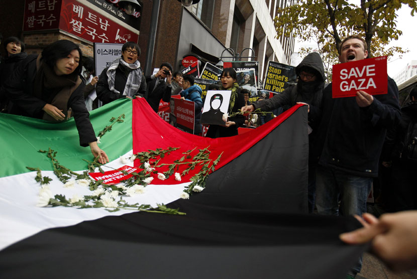  Seorang pengunjuk rasa menempatkan bunga pada bendera nasional Palestina dalam aksi demonstrasi mengutuk operasi militer Israel terhadap Jalur Gaza, di depan kedutaan Israel di Seoul, Jumat (16/11).  (Reuters/Kim Hong-Ji)