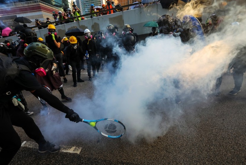 Seorang pengunjuk rasa menggunakan raket tenis untuk mengembalikan tabung gas air mata ketika polisi anti huru hara menembakkan gas air mata untuk membubarkan pengunjuk rasa di Hong Kong, Cina, Ahad (15/9). 