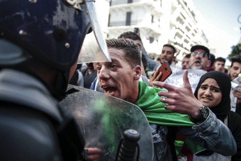 Seorang pengunjuk rasa mengonfrontasi polisi saat demonstrasi mahasiswa di Aljir, Aljazair, Selasa (9/4). Massa menolak penunjukan Abdelkader Bensalah sebagai presiden sementara.
