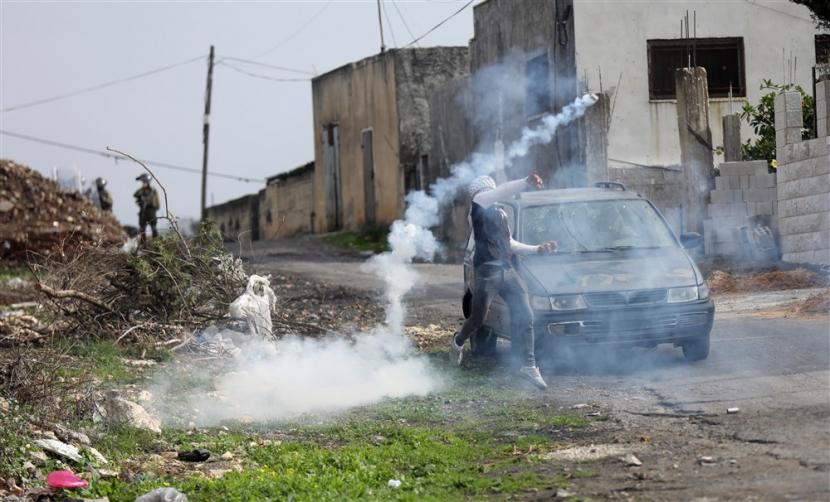  Seorang pengunjuk rasa Palestina melempar tabung gas air mata selama bentrokan dengan tentara Israel di desa Kafr Qaddum, dekat kota Nablus, Tepi Barat, 23 Desember 2022. Bentrokan itu menyusul protes terhadap permukiman Israel di daerah tersebut. Serikat Pekerja Eropa Boikot Produk yang Dibuat di Permukiman Israel