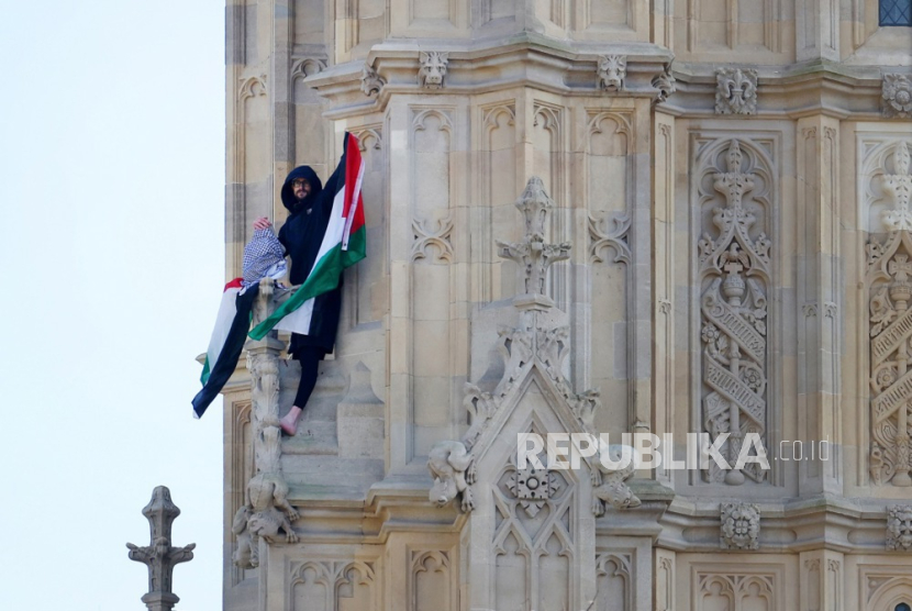 Seorang pengunjuk rasa pro Palestina mengibarkan bendera Palestina di atas Menara Elizabeth di London, Inggris, 8 Maret 2025. Polisi dan layanan darurat mencoba membujuk seorang pengunjuk rasa Palestina turun dari Big Ben setelah ia memanjat menara.