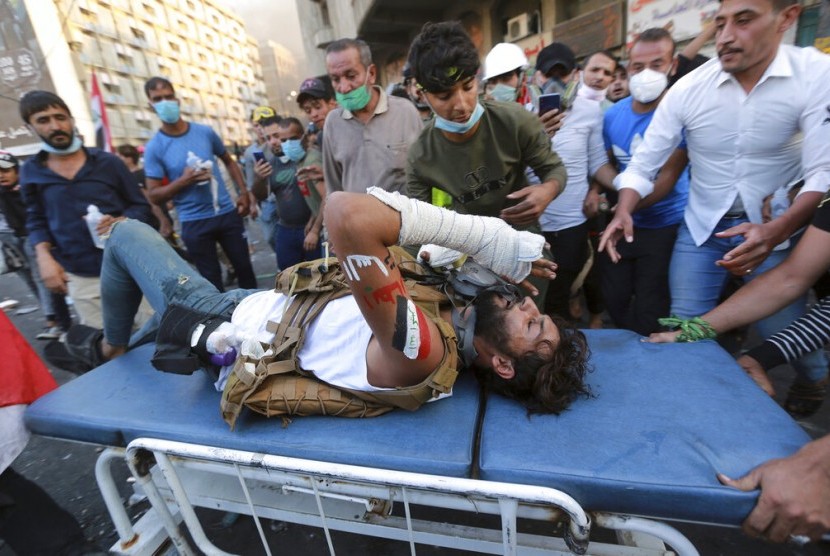 Seorang pengunjuk rasa yang terluka dibawa ke rumah sakit saat bentrokan dengan pasukan keamanan di Baghdad, Ira, Sabtu (9/11). 