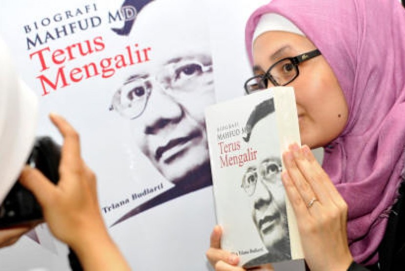 Seorang pengunjung acara peluncuran biografi Mahfud MD, Senin (4/3/2013) memegang buku tersebut yang berjudul 'Terus Mengalir'.