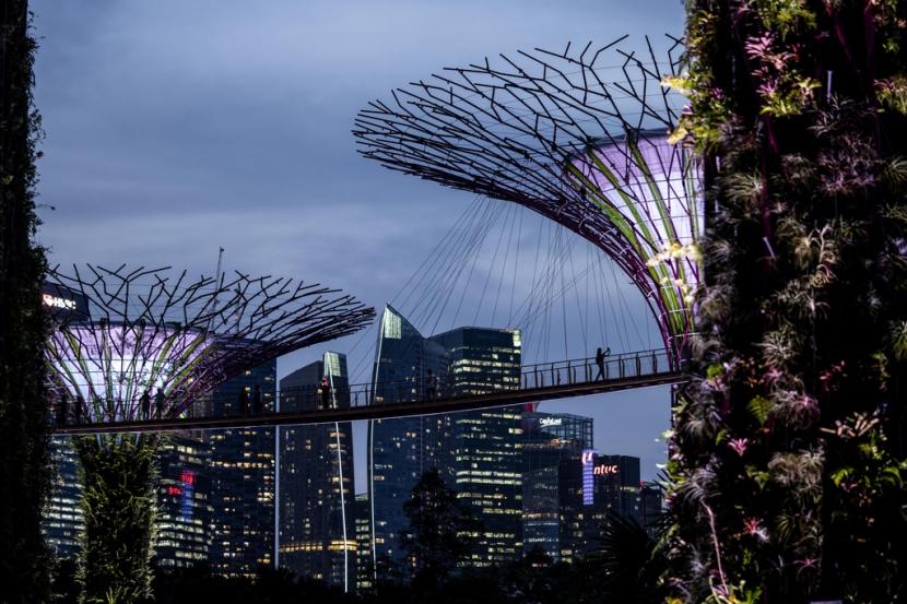 Seorang pengunjung berjalan di antara struktur Supertree di Gardens by the Bay saat senja menyelimuti cakrawala kota di Singapura, Senin, 17 Juli 2023. Menurut Henley Passport Index, paspor Singapura menduduki peringkat teratas sebagai yang terkuat di dunia. 