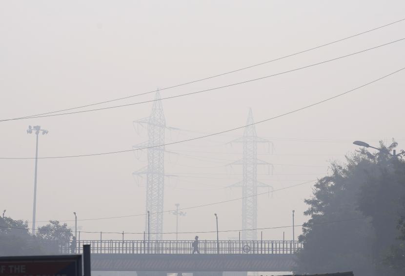 Seorang pengunjung kantor melintasi satu kaki di atas jembatan di tengah kabut pagi dan kabut asap beracun di New Delhi, India, Rabu, 17 November 2021. 
