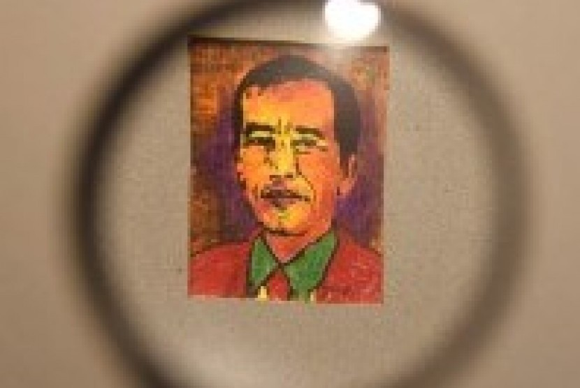 Seorang pengunjung menggunakan kaca pembesar untuk mengamati lukisan mini berukuran 3x4 cm bergambar Presiden Joko Widodo karya Jupri Abdullah saat pembukaan pameran di Surabaya, Jawa Timur, Jumat (2/11).