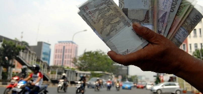 Seorang penjual jasa penukaran uang menjajakan uang pecahan di pinggiran Jalan Gajah Mada, Jakarta, Selasa (23/8). 