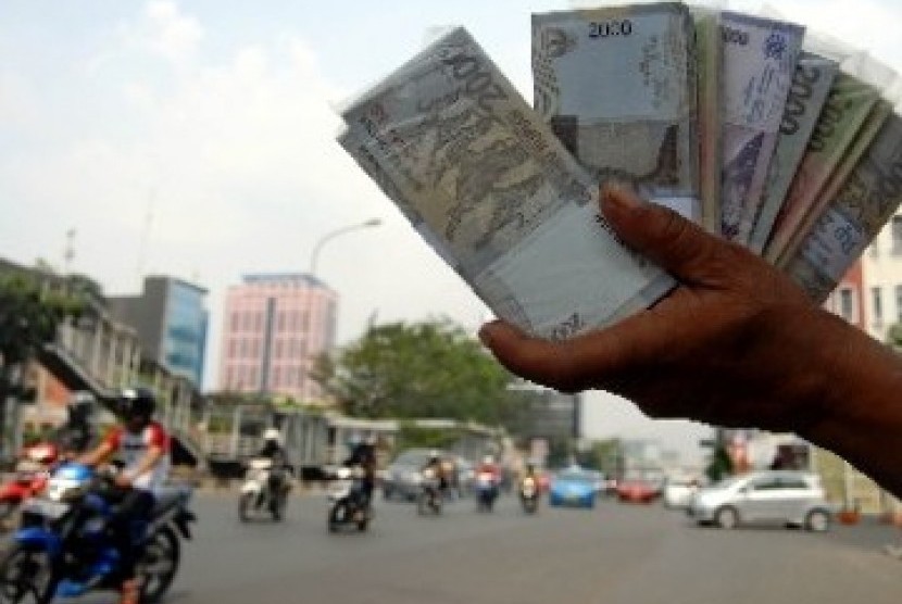 Seorang penjual jasa penukaran uang menjajakan uang pecahan di pinggiran jalan. ilustrasi 