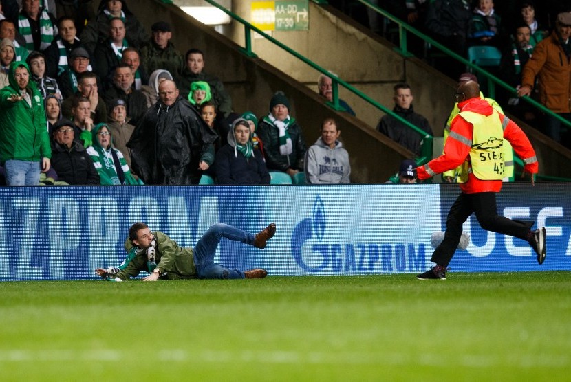 Seorang penonton (kiri) didekati oleh petugas keamanan (kanan) ketika laga antara Celtic dan Paris Saint-Germain di Celtic Park, Glasgow, Skotlandia, 12 September 2017.