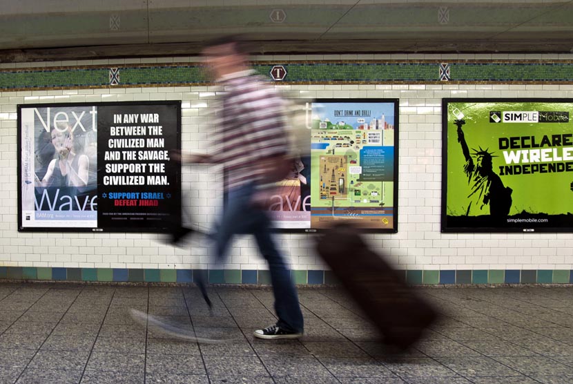  Seorang penumpang berjalan melewati sebuah poster anti-Islam yang dipasang di stasiun kereta bawah tanah Times Square, New York, Senin (24/9). Polisi New York Selidiki Serangan Terhadap Wanita Muslim di Kereta. (Bebeto Matthews/AP)