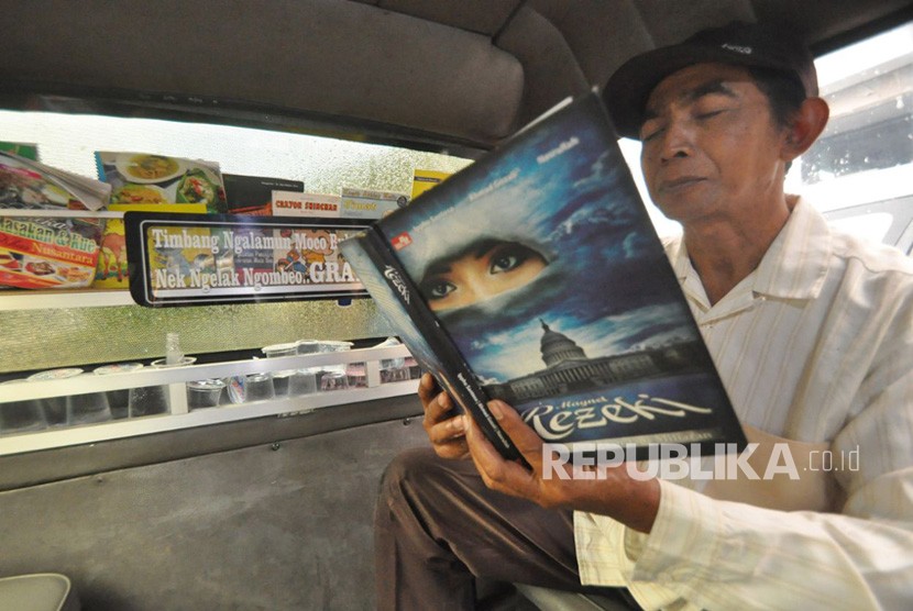 Seorang penumpang membaca buku dalam angkot Ungaran- Karangjati, Senin (19/2). Salah satu angkot di ibu kota Kabupaten Semarang menyediakan perpustakaan mini agar penumpang tidak jenuh dan gemar membaca. 