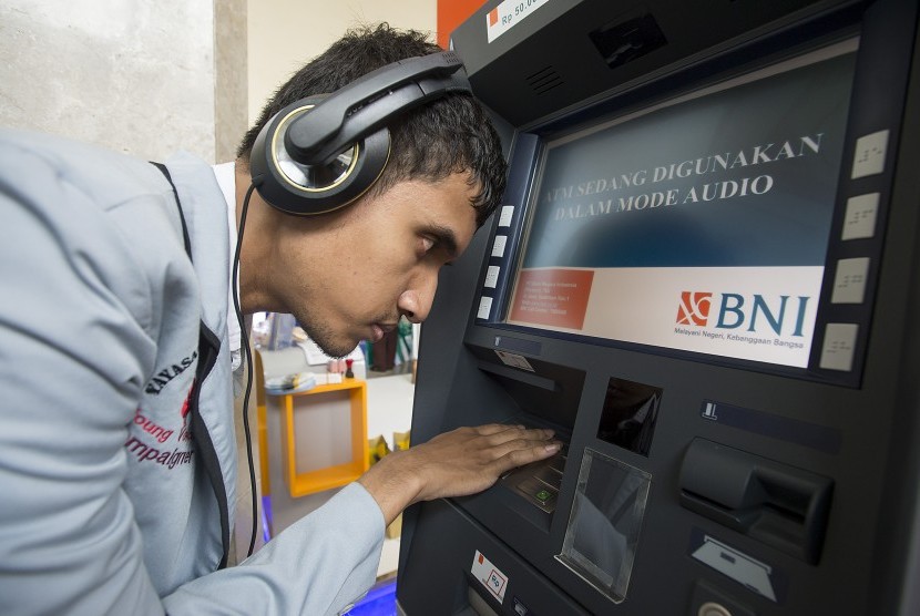 Seorang penyandang disabilitas mencoba bertransaksi di mesin ATM Bank BNI yang dilengkapi fasilitas bagi penyandang disabilitas.