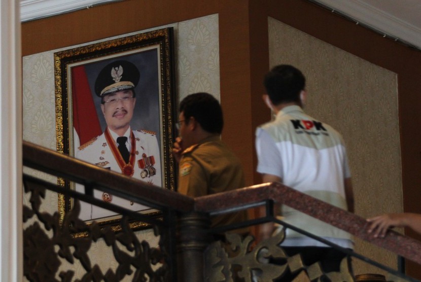 Seorang penyidik KPK melintas di depan foto Gubernur Sulawesi Tenggara Nur Alam yang terpajang di depan ruang kerjanya, Kendari, Sulawesi Tenggara, Selasa (23/8). 