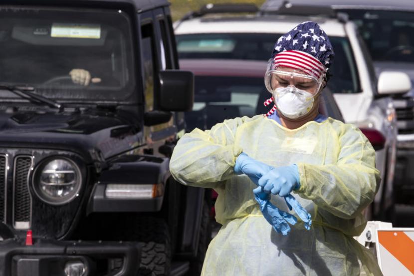  Seorang perawat mengganti sarung tangan setiap kali mengumpulkan sampel tes virus corona di sebuah lokasi drive through layanan pengujian virus corona di Stadion Diamond, Kalifornia, AS. 