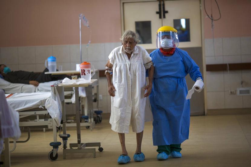 Seorang perawat menuntun pasien Covid-19 di unit intensif khusus Covid-19 di 2 de Mayo Hospital, Lima, Peru, Jumat (17/4).