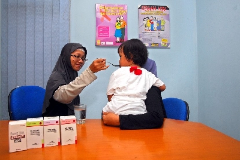 Seorang perawat tengah memberikan cairan Anti Retroviral Virus (ARV) sebagai obat memperlambat perkembangan virus kepada anak dengan HIV/AIDS.