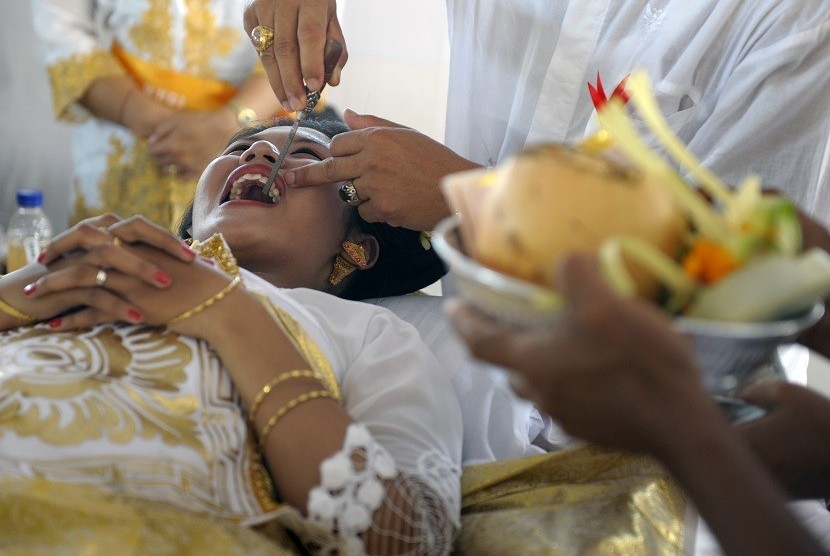 Seorang perempuan Bali mendapat gosokan kikir pada giginya saat ritual (ilustrasi) 