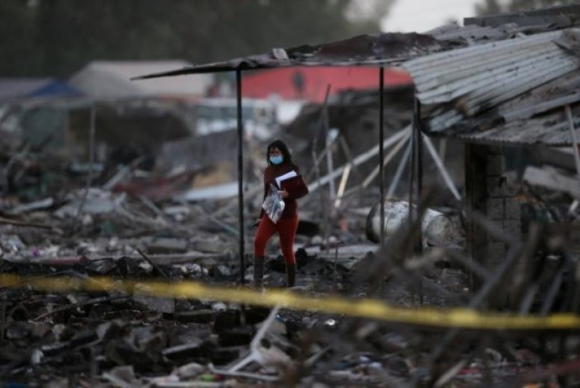 Seorang perempuan berjalan di tengah puing-puing rumah yang hancur akibat ledakan di pasar kembang api San Pablito di Tultepec, Meksiko, 20 Desember 2016.