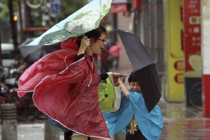 Seorang perempuan dan anaknya memegang payung mereka dengan erat, saat angin kencang yang dipicu oleh topan Usagi bergerak mendekati Taipei, Taiwan, Sabtu  (21/9).