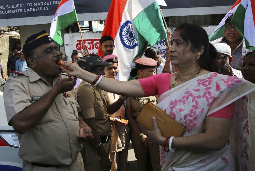  Seorang perempuan di Mumbai, India menawarkan permen ke aparat kepolisian sebagai bentuk perayaan terhadap laporan dijatuhkannya hulu ledak dari pesawat India di daerah teritorial Pakistan, Selasa (26/2).