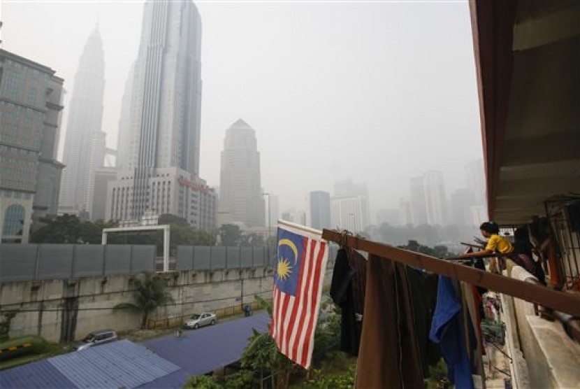 Seorang perempuan (kedua dari kanan) menjemur pakaian tidak jauh dari Menara Kembar Petronas di Malaysia yang diselimuti kabut asap. ilustrasi