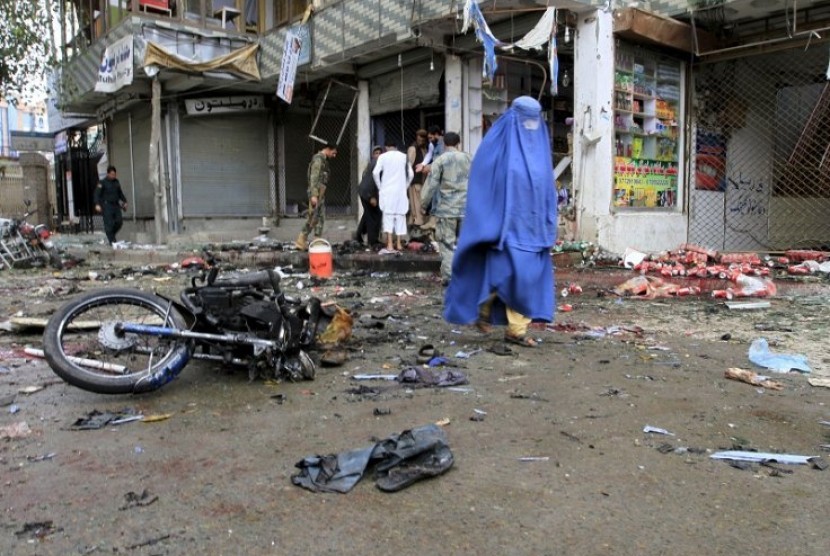 Seorang perempuan melintas di lokasi ledakan bom bunuh diri di Jalalabad, Sabtu (18/4).