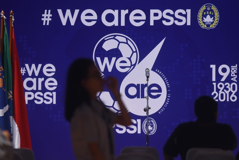  Seorang perempuan melintasi backdrop bertuliskan We are PSSI ketika syukuran HUT ke-86 PSSI di Stadion Utama Gelora Bung Karno, Jakarta, Selasa (19/4). 
