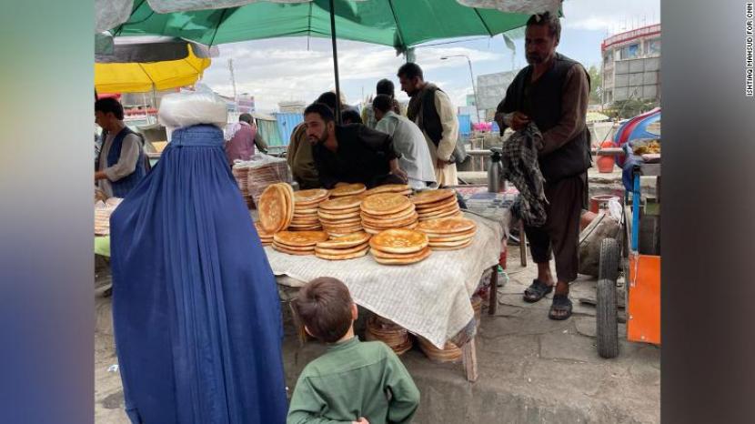 Seorang perempuan membawa roti Naan di Pasar Kabul,