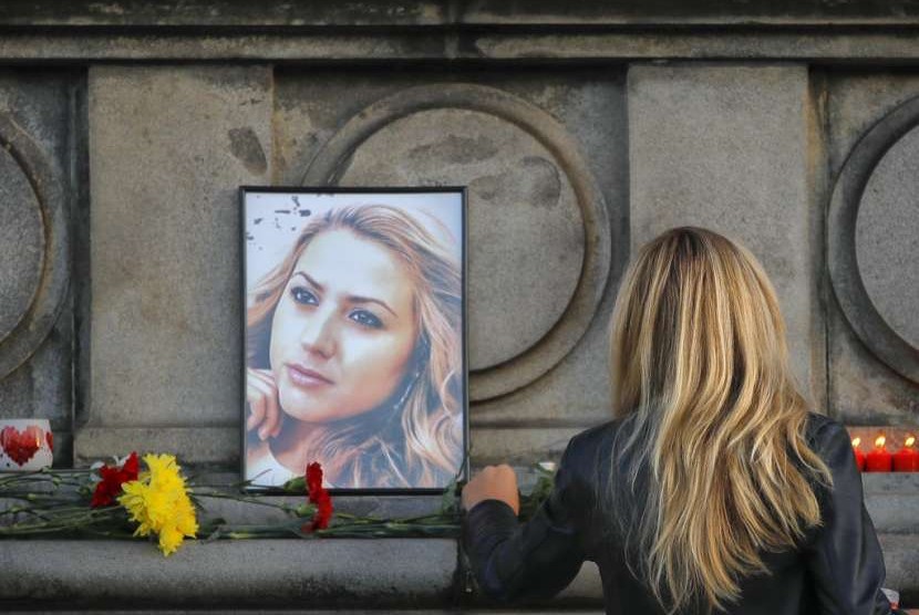 Seorang perempuan memberikan bunga di depan foto Viktoria Marinova, seorang wartawan televisi Bulgaria yang diperkosa dan dibunuh setelah melaporkan kasus korupsi, Senin (8/10).