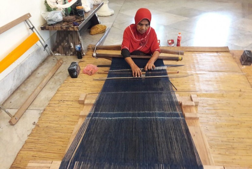 Seorang perempuan membuat kain tenun ende