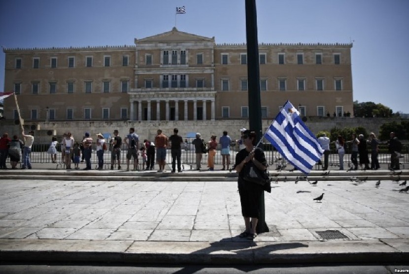 Seorang perempuan memegang bendera Yunani dan bendera Siprus yang berukuran lebih kecil di depan gedung parlemen Yunani di Athena, dalam aksi mogok Hari Buruh 2013 (May Day). Angkutan kapal feri dan kereta api di Yunani terhenti akibat aksi mogok ini (1/5)
