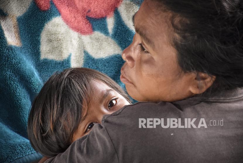 Seorang perempuan mengendong anaknya di tenda perawatan pascagempa di Desa Sembalun Bumbung, Kecamatan Sembalun, Selong, Lombok Timur, NTB, Minggu (29/7). 