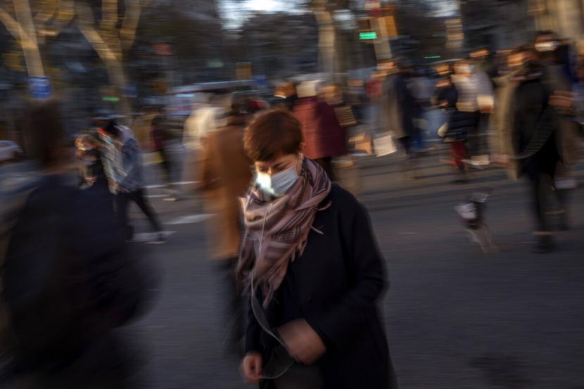 Seorang perempuan menggunakan masker berjalan di pinggiran Barcelona, Spanyol, Rabu (12/1/2022).