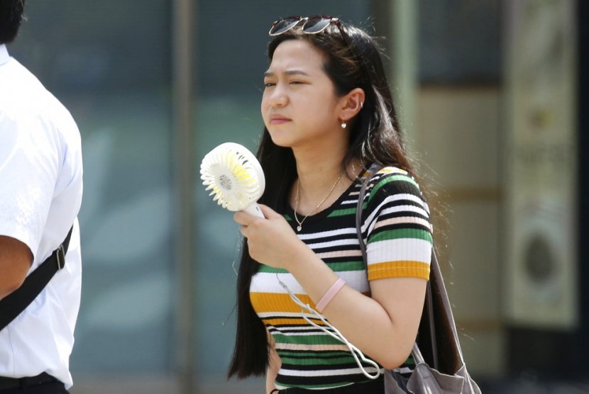 Seorang perempuan mengusir panas dengan kipas portable di Tokyo, Senin (23/7). Jepang sedang dilanda panas ekstrem dengan suhu mencapai 41 derajat Celcisu.