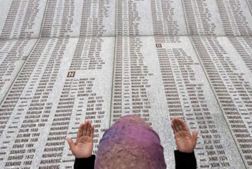 Seorang perempuan Muslim Bosnia berdoa di dinding peringatan berisi nama korban Pembantaian Srebrenica di Potocari Memorial Center.