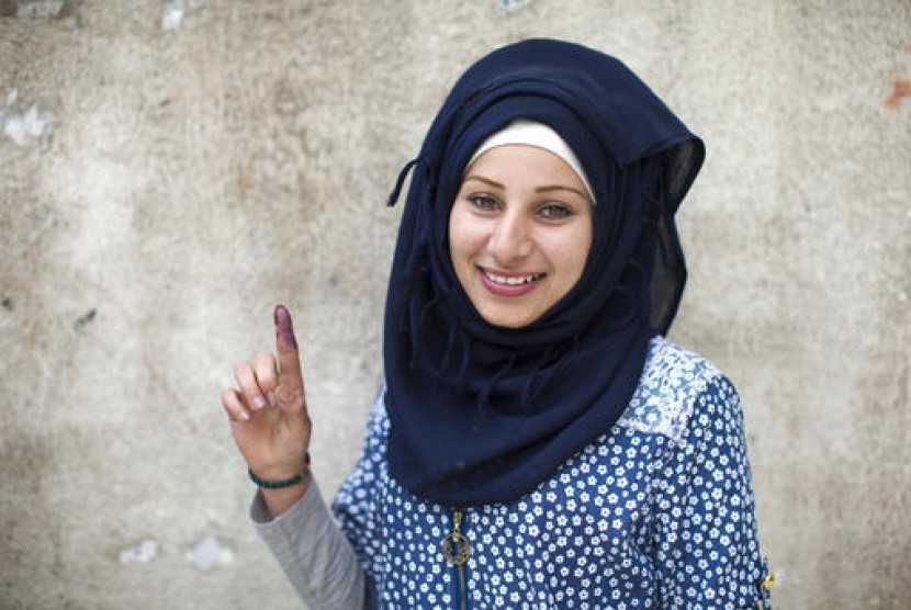 Seorang perempuan Suriah berpose menunjukkan jarinya yang bertinta usai memberikan suara dalam pemilihan parlemen di Damaskus, Suriah, Rabu, 13 April 2016.