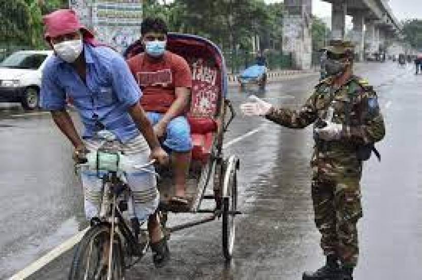 Seorang personel tentara Bangladesh memberi isyarat kepada seorang pengemudi becak di sebuah pos pemeriksaan jalan di Dhaka