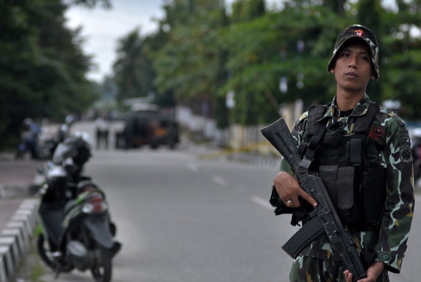 Seorang personil Brimob bersenjata lengkap berjaga-jaga di jalan raya tepat di depan markas Polsek Kota untuk menghalau warga sipil menuju tempat kejadian perkara (TKP) adanya benda diduga berisi bom, di Poso, Sulawesi Tengah, Rabu (11/3).