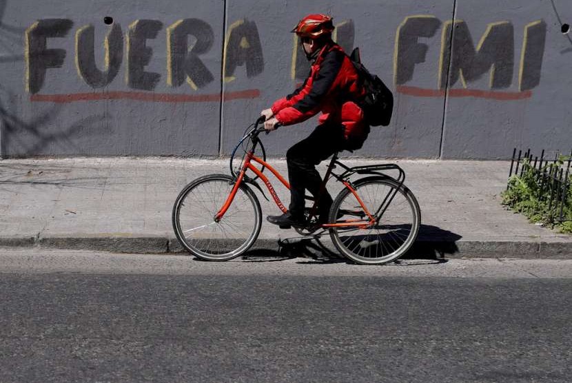 Seorang pesepeda melintasi grafiti berbahasa Spanyol di jalan di Buenos Aires, Argentina, Selasa (4/9). Grafiti tersebut berarti 'Pergilah IMF'. Beberapa pekan terakhir, krisis Argentina meningkat dan memaksa negara tersebut berutang ke IMF.