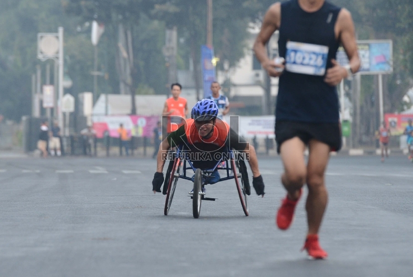   Seorang peserta difabel Jakarta Mandiri Marathon melintasi Kawasan Kota Tua, Jakarta Barat, Ahad (25/10). (Republika/Raisan Al Farisi)