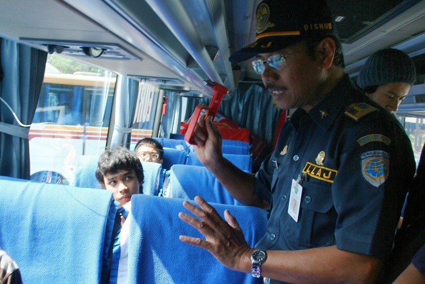 Seorang petugas dari tim gabungan Kepolisian dan Dishub memberitahukan cara penggunaan palu pemecah kaca kepada sejumlah penumpang dan awak bus saat razia angkutan mudik Lebaran di Terminal Arjosari, Malang, Jatim