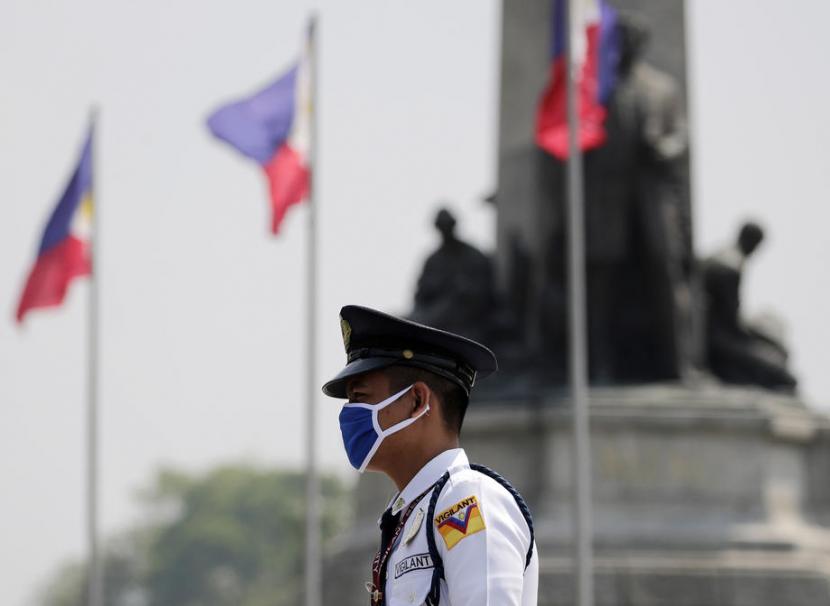Seorang petugas di Manila mengenakan masker. Para wali kota dari 16 wilayah Metro Manila mengumumkan jam malam pada Sabtu dan mendesak mal-mal tutup selama sebulan. Ilustrasi.