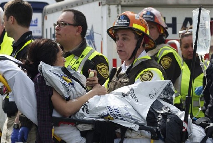 Seorang petugas gawat-darurat terlihat menenangkan seorang wanita yang terluka akibat bom yang meledak di dekat garis finis Lomba Maraton Bo)ston, Selasa (16/4) pagi WIB.
