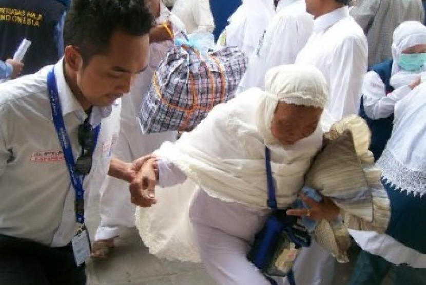 seorang petugas haji PPIH 2009 membantu jamaah yang baru tiba dari Madinah. Ilustrasi