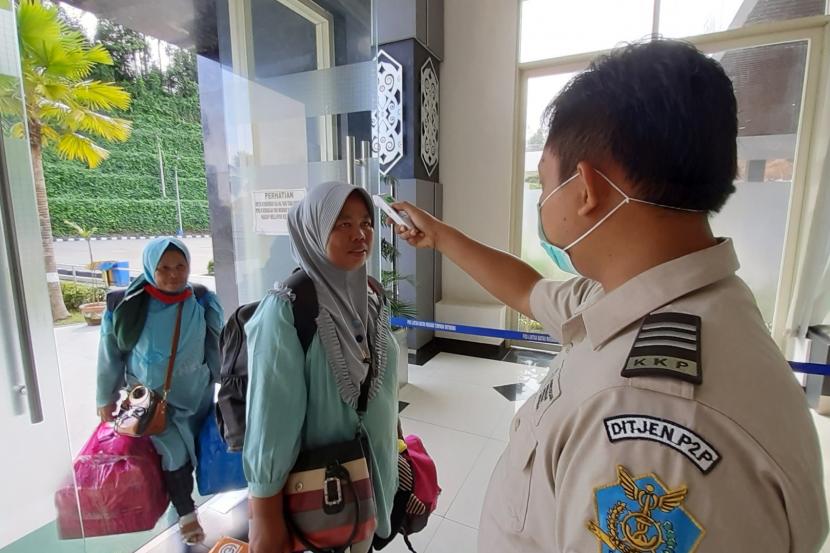 Seorang petugas Kantor Kesehatan Pelabuhan (KKP) Entikong mengukur suhu tubuh Warga Negara Indonesia (WNI) yang pulang dari Malaysia di Pos Lintas Batas Negara (PLBN) Entikong di Kabupaten Sanggau, Kalimantan Barat, Kamis (19/3/2020). 