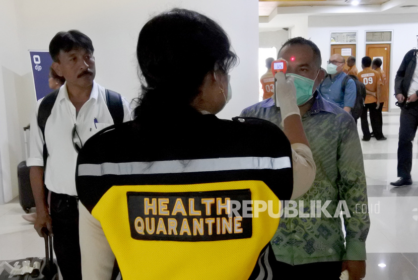Seorang petugas Kantor Kesehatan Pelabuhan (KKP) memeriksa suhu tubuh penumpang pesawat yang baru turun di terminal kedatangan domestik bandara El Tari Kupang NTT, Rabu (04/03/20).(Antara/Kornelis Kaha)