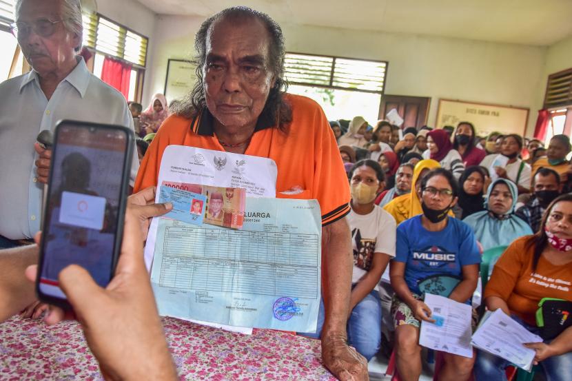 Seorang petugas Kantor Pos memotret warga penerima bantuan sosial di kantor Negeri Waai, Kabupaten Maluku Tengah,Kamis (14/4/2022). Belanja negara untuk masyarakat telah mencapai Rp 492 triliun.